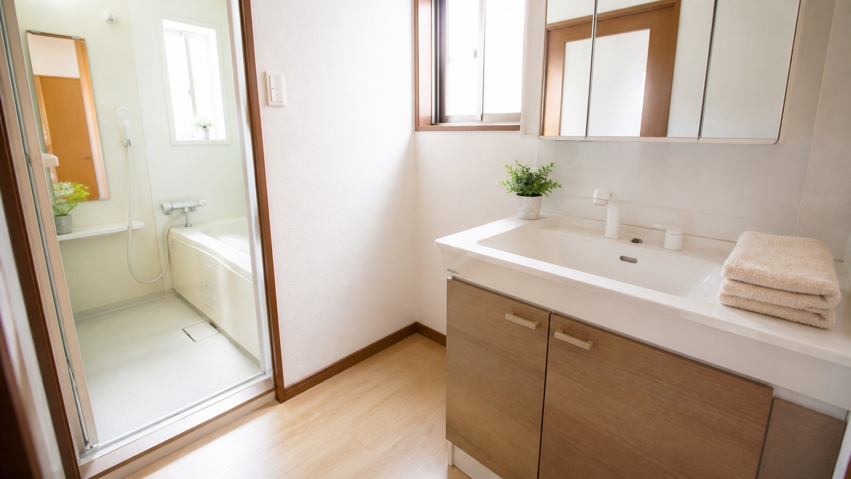 清掃後にタオルと小さな植物が整えられた、日本の住まいの明るい洗面所の説明用イメージ